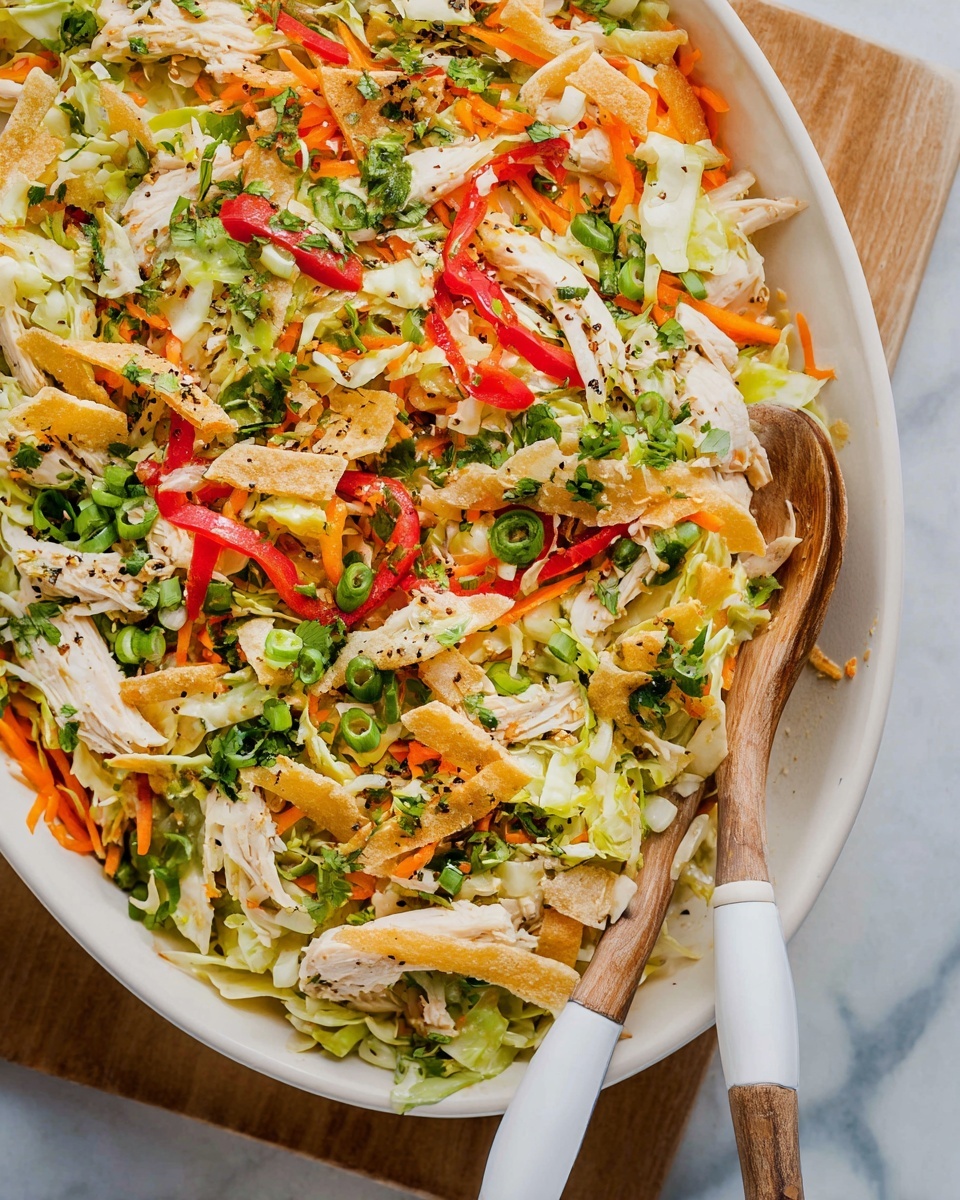 The dish is a colorful salad served in a white oval bowl filled with several layers of food. The base layer has shredded light green cabbage mixed with thin strips of bright orange carrot. On top of this, there are pieces of pale white cooked chicken and thin slices of crispy beige chips or crackers. Scattered over the salad are small rounds of light green spring onions and chopped fresh green herbs like parsley or cilantro. There are also vibrant red slices of bell pepper adding contrast. The whole dish is topped with a sprinkle of black pepper and herbs, giving it a fresh and seasoned look. Two wooden utensils with white handles rest inside the bowl, placed on a white marbled surface. Photo taken with an iphone --ar 2:3 --v 7