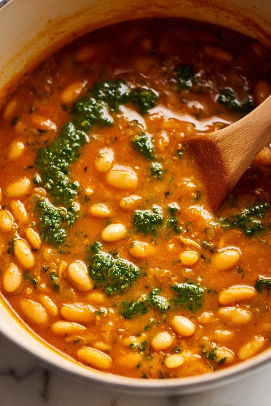 A close-up of a black bowl filled with thick, creamy soup that is light brown with visible white beans and green herb flecks throughout. A woman's hand is dipping a piece of torn white bread topped with a smooth spread into the soup, capturing the texture of the soft bread and creamy topping mixing with the chunky soup. The background features a white marbled surface and another blurred bowl can be seen in the top right corner. photo taken with an iphone --ar 2:3 --v 7
