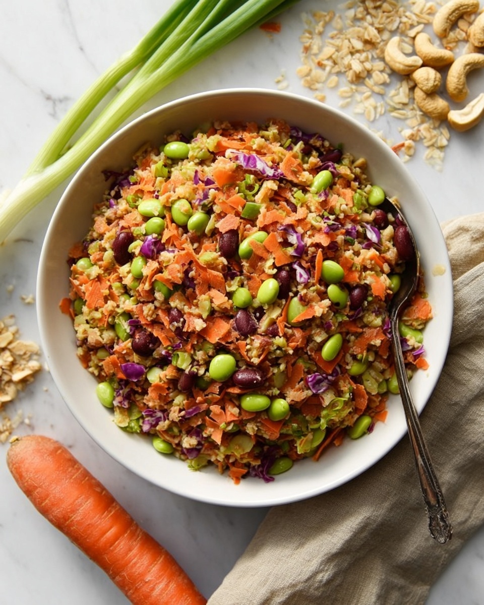 The image shows a white bowl filled with a colorful mixed salad that appears to have around five layers of ingredients. The base layer is light brown cooked grains, mixed evenly with small dark red beans and bright orange shredded carrots. Scattered bright green edamame and finely chopped celery add pops of color throughout. Purple cabbage pieces can also be seen, adding texture and a hint of purple color. The bowl is placed on a white marbled surface, surrounded by a whole carrot, green onions, some cashews, and uncooked grains. Two black and gold utensils rest inside the bowl. Photo taken with an iphone --ar 2:3 --v 7