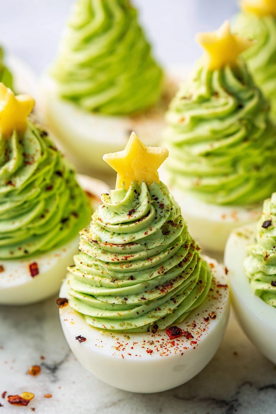 The image shows several halved boiled eggs placed on a white marbled surface, each topped with a tall swirl of bright green creamy mixture piped to look like a small Christmas tree. The green filling has a smooth, textured appearance with fine ridges from the piping. One egg is topped with a small yellow star-shaped slice, resembling a tree topper. The green swirls are sprinkled evenly with small bits of red and black seasoning, adding color contrast. The eggs are arranged close together, and the photo focuses closely on the front eggs with a soft, blurred background. Photo taken with an iphone --ar 2:3 --v 7