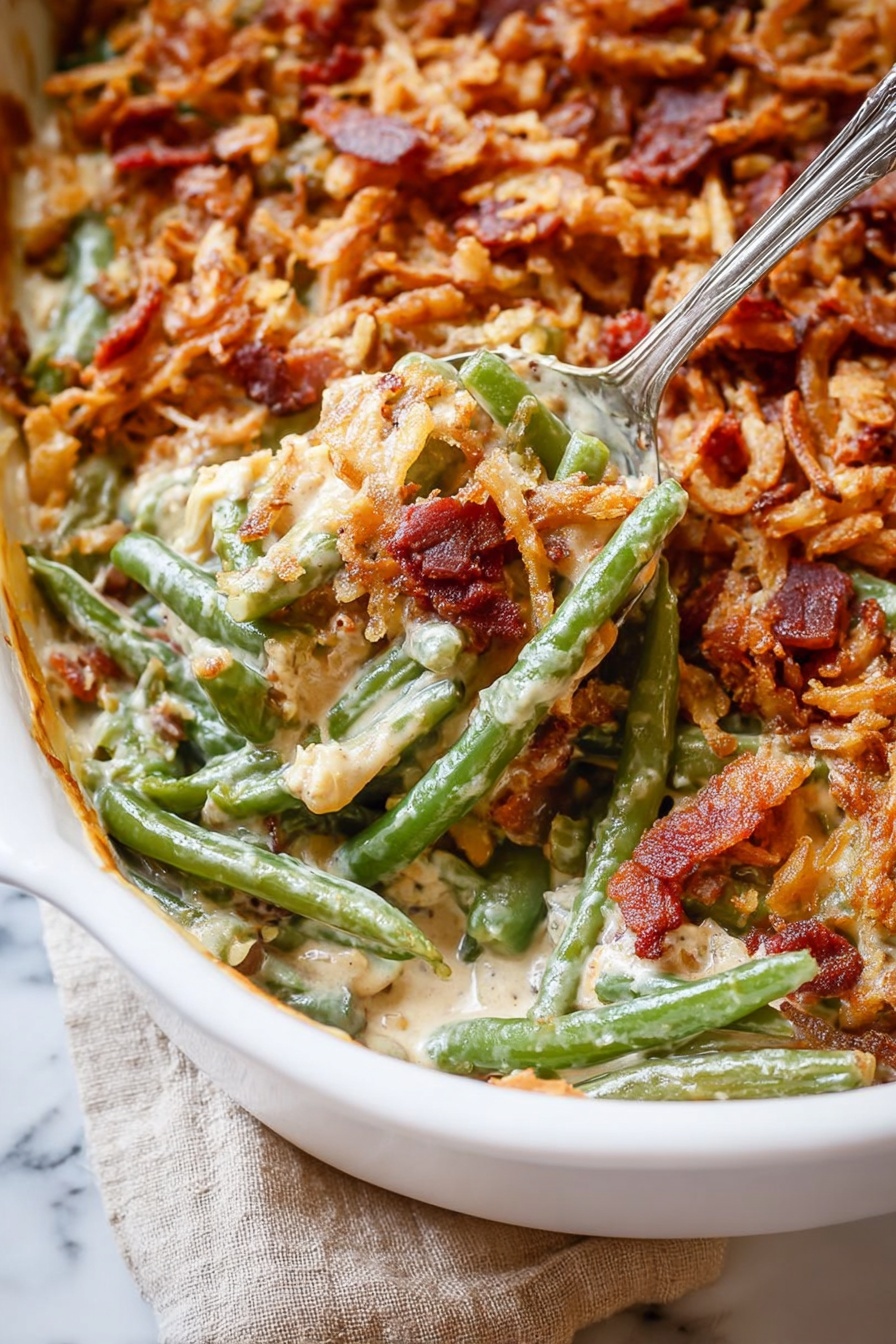 The image shows a close-up of a baked green bean casserole in a white dish. The dish has three main layers: the bottom layer is green beans with a shiny, soft texture; the middle layer is a creamy sauce mixed with small crispy bacon pieces scattered throughout, adding spots of red-brown color; the top layer is a crunchy, golden brown mix of fried onions and more bacon bits, creating a textured, uneven surface. A silver spoon is scooping a portion, lifting green beans and sauce from the dish. The dish sits on a white marbled surface with a beige cloth partially visible. photo taken with an iphone --ar 2:3 --v 7