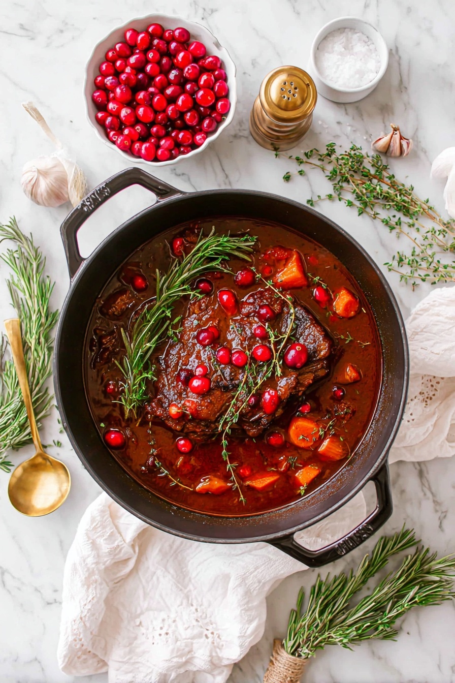 The image shows a black pot filled with a rich brown stew that has a large piece of cooked meat in the center, covered with a deep red sauce. Scattered on top and around the meat are bright red cranberries and chunks of orange carrots. A sprig of fresh green rosemary lies on top of the meat, adding a touch of color. The pot sits on a white marbled surface with a white cloth nearby. Around the pot, there is a white bowl filled with red cranberries, a small white dish with garlic, a salt container with a gold spoon, a pepper grinder, and some sprigs of rosemary and thyme. Two knives and two forks rest on the surface to the right of the pot. The whole scene feels fresh and inviting. photo taken with an iphone --ar 2:3 --v 7