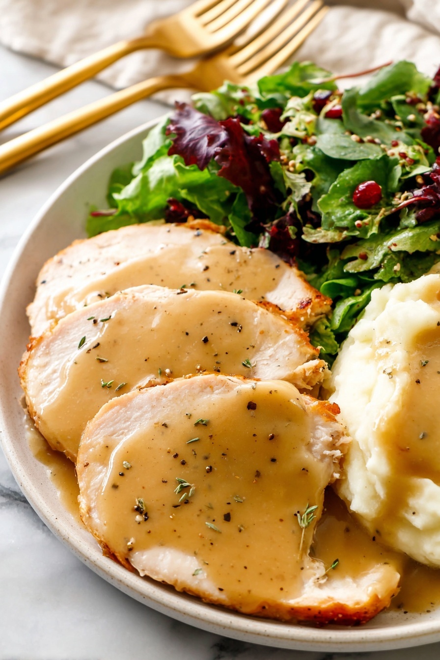 The dish features three thick slices of light brown turkey meat, each covered with a smooth, shiny layer of golden-brown gravy speckled with black pepper, arranged on the left side of a white plate. To the right is a mound of creamy white mashed potatoes topped with the same golden-brown gravy that slightly spills over the edges. Behind the turkey and potatoes, there is a fresh mixed green salad with dark green and purple leafy greens, small seeds, and bits of red fruit, providing a bright contrast to the dish. The plate rests on a white marbled surface and there are golden serving utensils placed near the top. Photo taken with an iphone --ar 2:3 --v 7