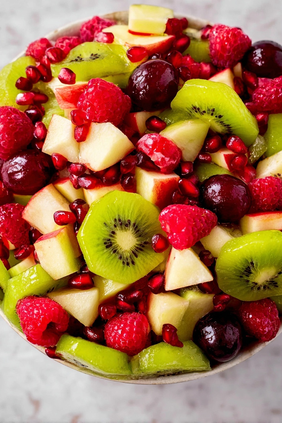 A bright fruit salad with three main layers seen from above: the bottom layer is light green sliced kiwi with a soft texture, the middle layer consists of small white apple pieces with a firm texture, and the top layer is made of bright red raspberries, deep red grape pieces, and shiny red pomegranate seeds scattered around, all placed on a white marbled surface photo taken with an iphone --ar 2:3 --v 7