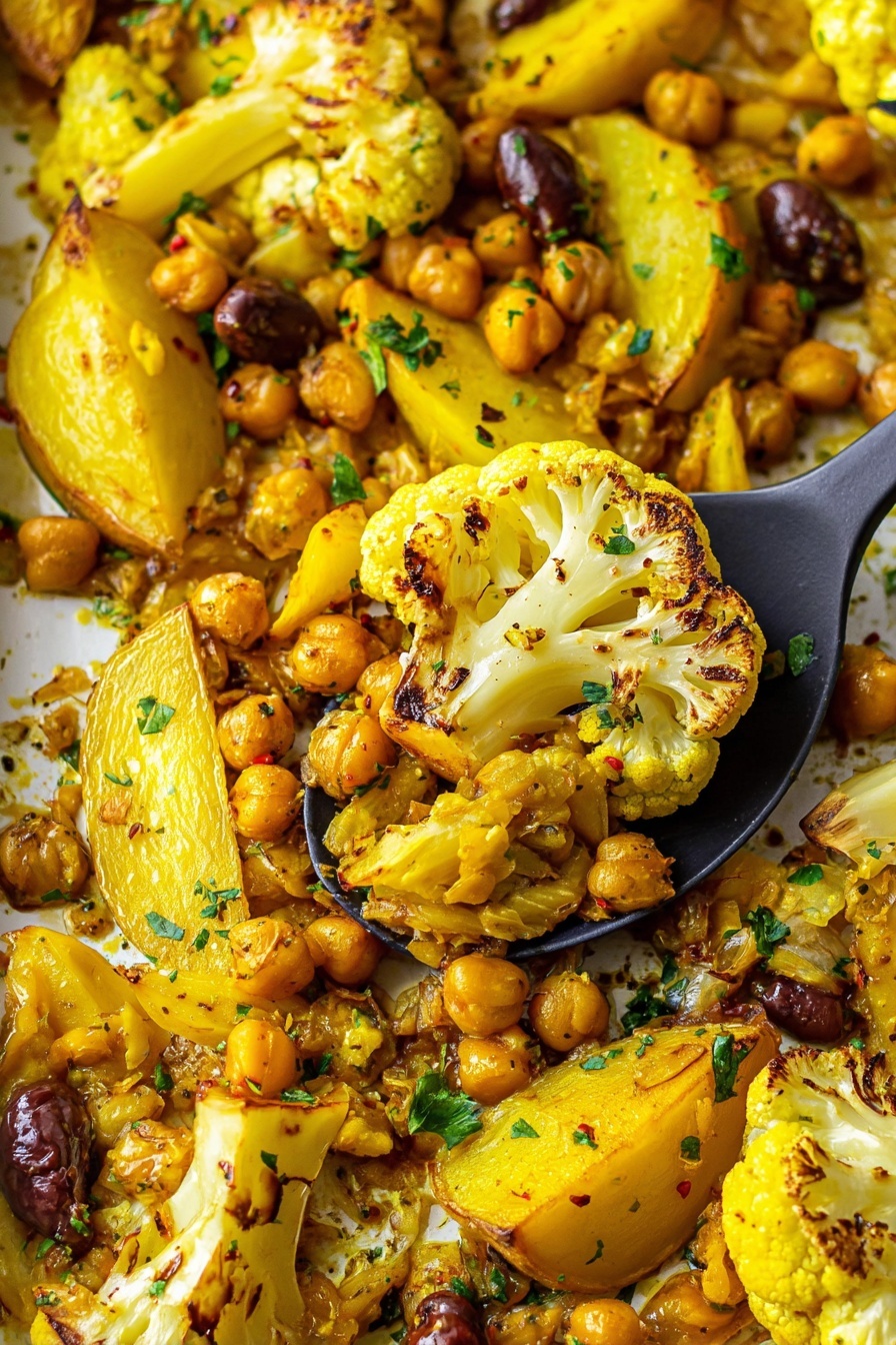 The image shows a close-up of roasted vegetables and chickpeas on a white marbled surface, with a black serving spoon lifting a portion. The dish has bright yellow roasted cauliflower pieces with charred brown edges as the main layer, mixed with golden-yellow potato wedges and light brown chickpeas scattered throughout. There are also dark brown olives spread evenly across the dish. Small green herb bits are sprinkled all over, adding a fresh touch. The colors differ from yellow to brown with specks of green, and the texture looks crispy and soft together. Photo taken with an iphone --ar 2:3 --v 7