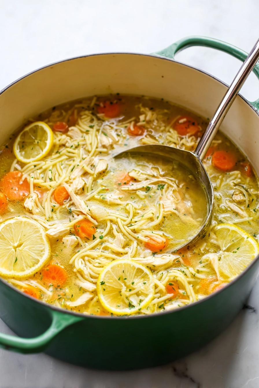 A green pot filled with a light yellow chicken noodle soup sits on a white marbled surface, featuring a mix of thin noodles, small round orange carrot slices, and shredded white chicken pieces floating in the broth. Three thin lemon slices rest on the side of the soup near the top edge, adding a bright yellow accent. A large silver ladle with a reflective surface is placed inside the pot on the right side, touching the soup. Photo taken with an iphone --ar 2:3 --v 7
