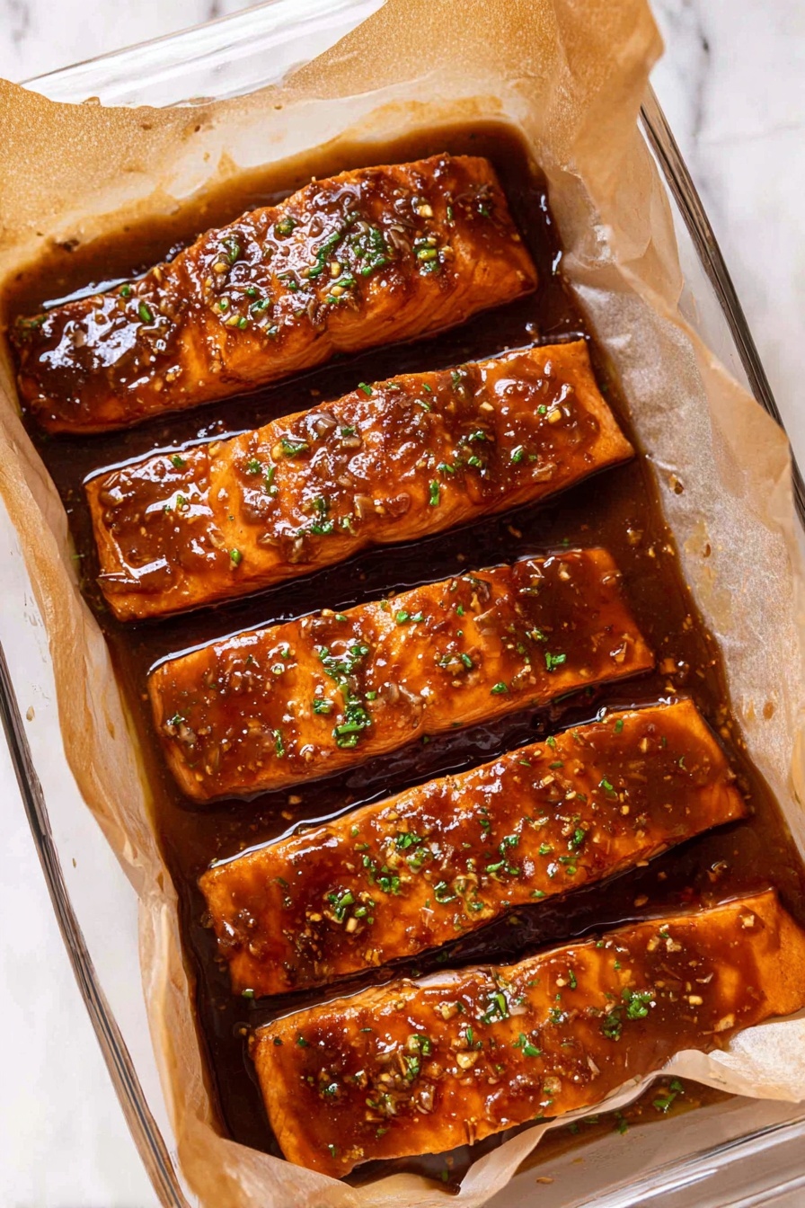 Four long rectangular pieces of cooked salmon with a shiny, thick, brown sauce covering all around them, placed side by side in a clear glass rectangular dish lined with light brown parchment paper. Small green herb bits are sprinkled on top of the salmon. The sauce has a slightly sticky texture with visible bits of garlic or seeds. The dish is set on a white marbled surface. photo taken with an iphone --ar 2:3 --v 7