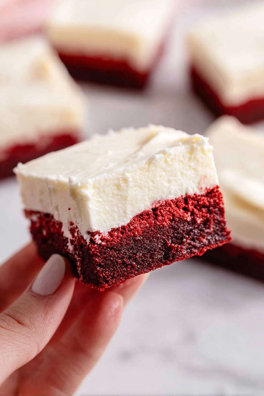 A silver rectangular baking pan sits on a white marbled surface with thick, smooth, deep red batter being poured into it from a clear glass bowl positioned at the top right. The rich batter flows evenly in a wide, glossy layer inside the pan, showing a shiny texture with small air bubbles. photo taken with an iphone --ar 2:3 --v 7