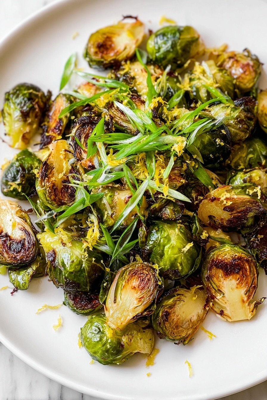 A white plate holds a single layer of roasted Brussels sprouts, all halved and browned with crispy, dark caramel edges and tender green inner leaves. Bright green sliced scallions are scattered on top, adding a fresh touch. Light yellow zest is sprinkled over the dish, giving it a textured look. The plate sits on a white marbled surface. photo taken with an iphone --ar 2:3 --v 7