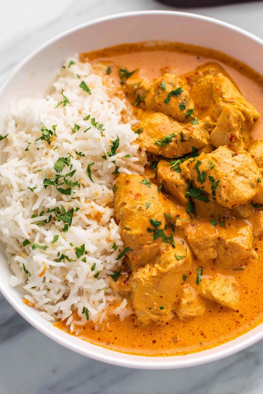 A white bowl filled with raw chicken pieces covered in a thick red sauce with visible onion chunks mixed in. The chicken looks soft and partly covered by the sauce, spread unevenly in the bowl. A woman's hand is holding the bowl on the left side, and another woman's hand is stirring the mixture with a wooden spoon, creating a slight blur in motion. The background is a white marbled surface. photo taken with an iphone --ar 2:3 --v 7